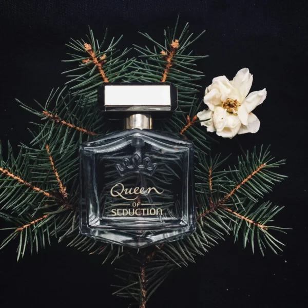 A perfume bottle styled with conifer leaves and a white flower, conveying a classy and seductive aroma.