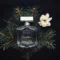 A perfume bottle styled with conifer leaves and a white flower, conveying a classy and seductive aroma.